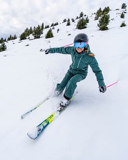 A skier enjoys the snowy slopes of Cerler Huesca in Aragon Spain with a chalet in the background and a child learning to ski nearby. A vibrant winter sports scene unfolds under clear skies.