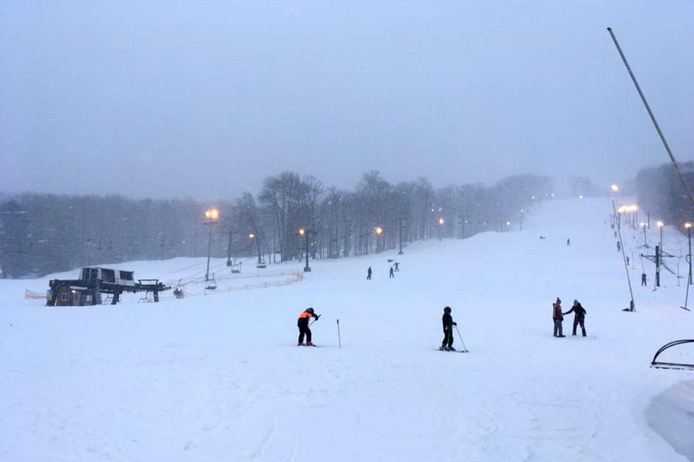 A winter sports scene at Sawmill Mountain Resort, Pennsylvania, featuring a skier amidst stunning snowy scenery with the ski resort facilities in the background.