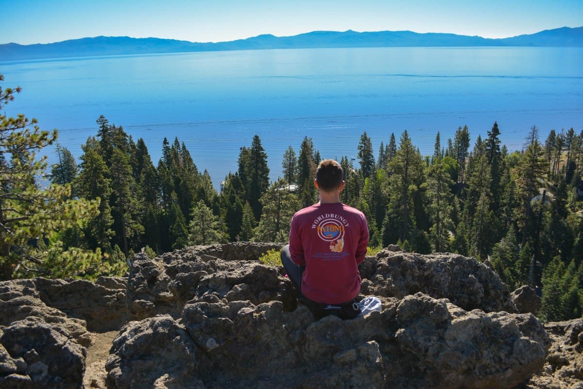 Eagle Rock in USA - a woman sitting on top of a mountain looking out over a lake.