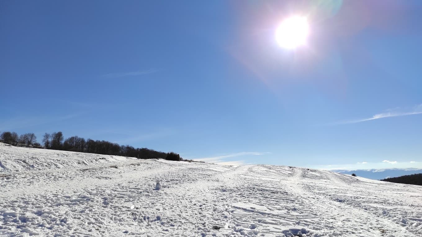 Stanic in North Macedonia - the sun is shining over a snowy hill.