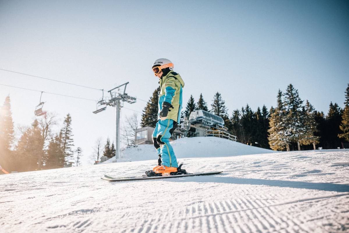 Trije Kralji in Slovenia - a snowboarder rides down a slope on a sunny day.