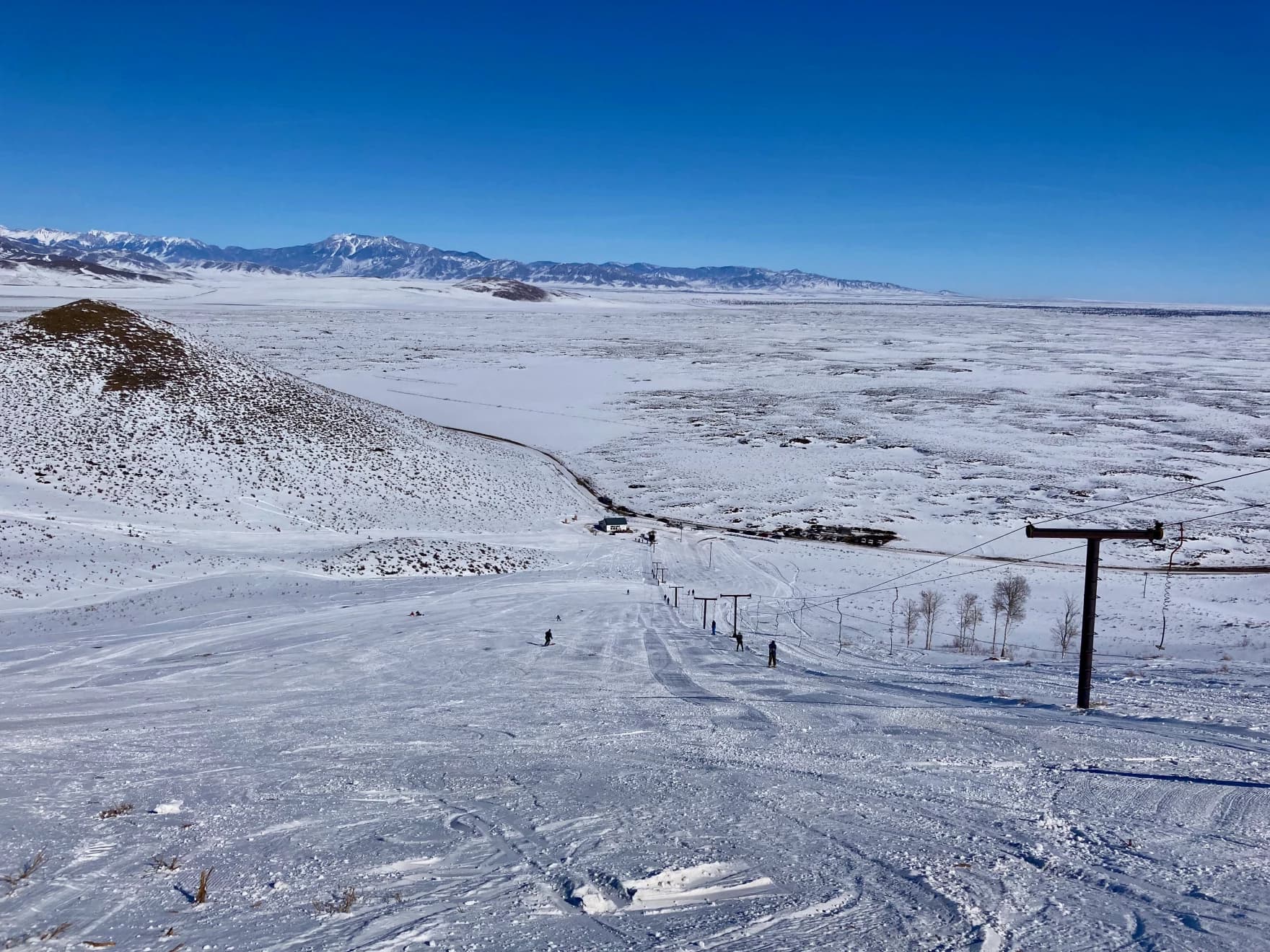 A winter sports scene at Blizzard Mountain, Idaho, featuring stunning snowy scenery. Ski resort and chalet visible in the background.