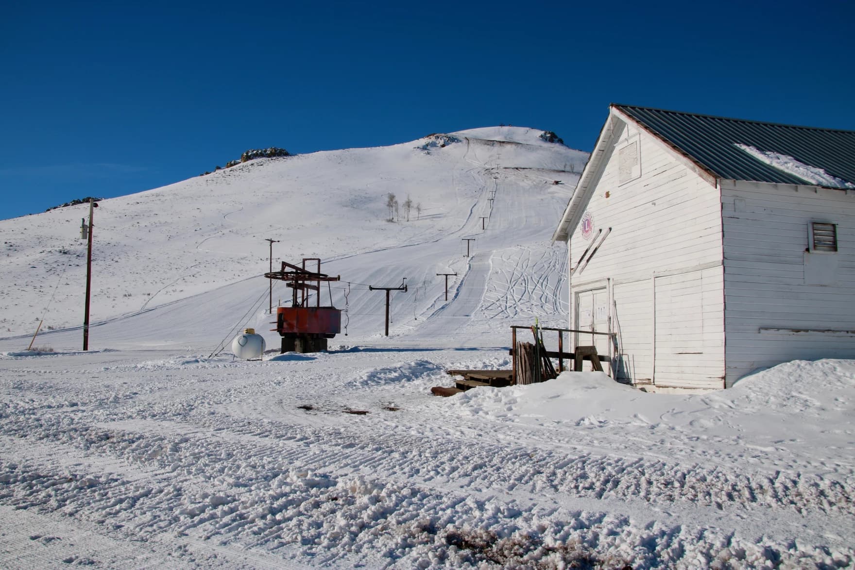 View of Blizzard Mountain in Idaho featuring a bustling winter sports centre and ski resort with a picturesque chalet and mountain hut nearby. A quintessential winter sports scene unfolds in the snowy landscape.