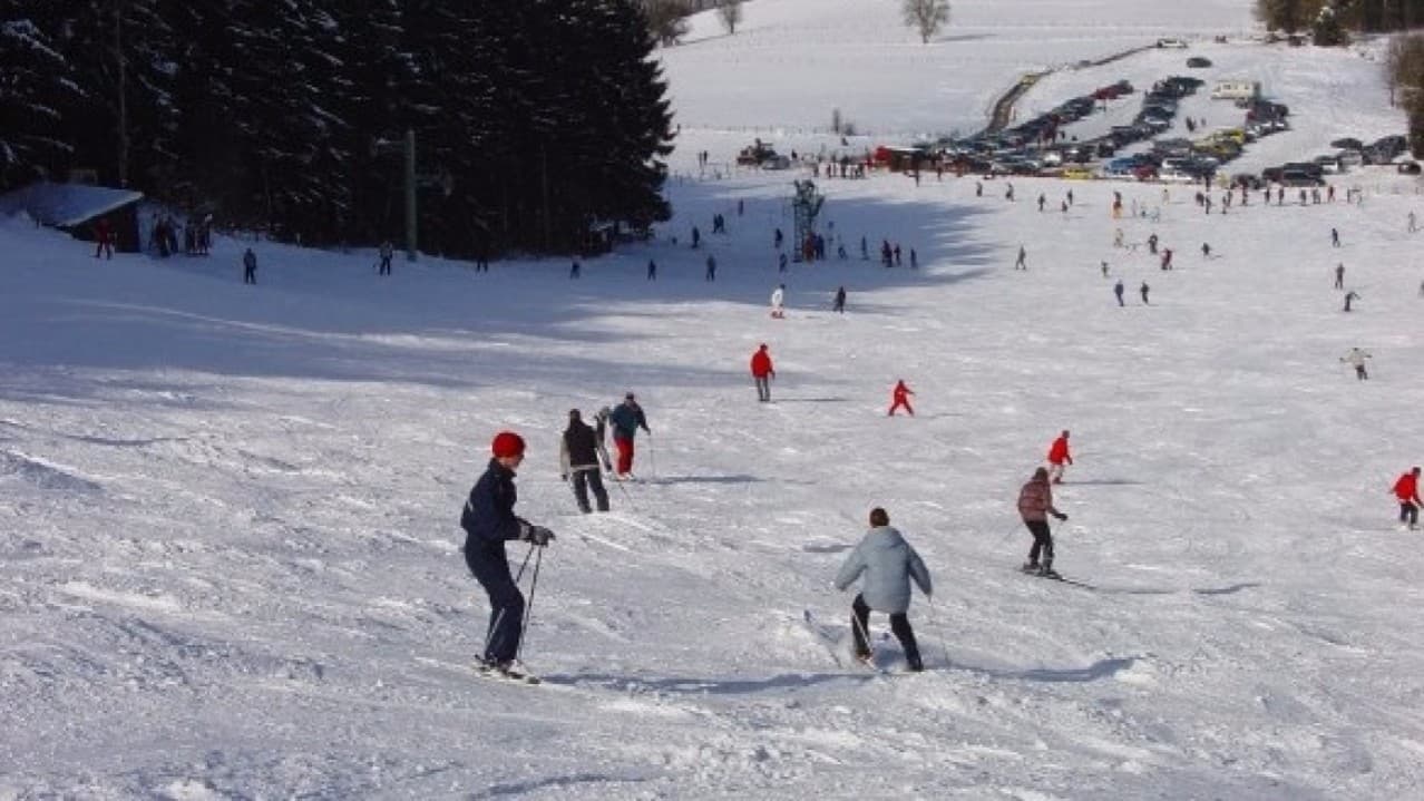 Mont des Brumes in Belgium - a group of people skiing down a snowy hill.