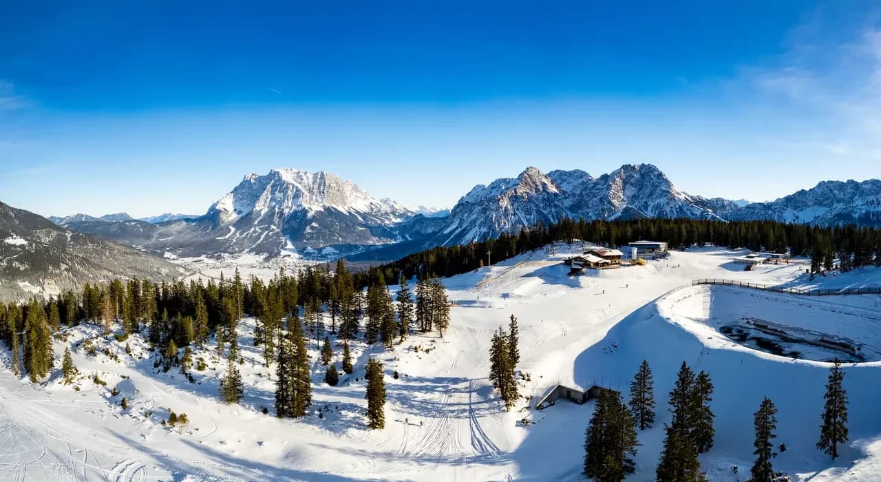 Karlift – Heiterwang in Austria - a snow covered mountain with trees and mountains in the background.
