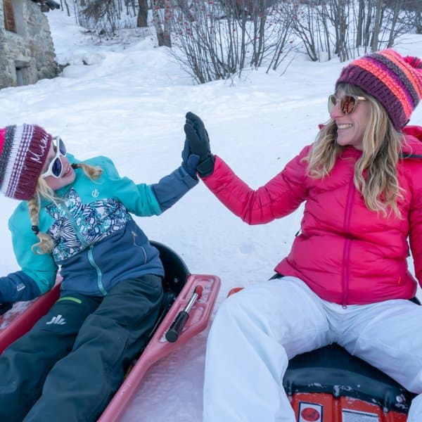 A family is enjoying skiing on a beautiful winter day at Puy Saint Vincent in France. The scene encapsulates the essence of winter sports. A snowmobile can also be seen in the background.