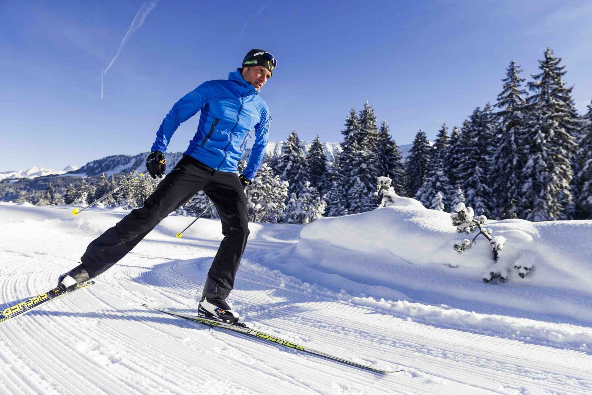 A skier enjoys a winter sports scene in Walmendingerhorn | Heuberg – Mittelberg | Hirschegg, Bregenz, Vorarlberg, Austria, with a challet peeking through the snowy landscape.