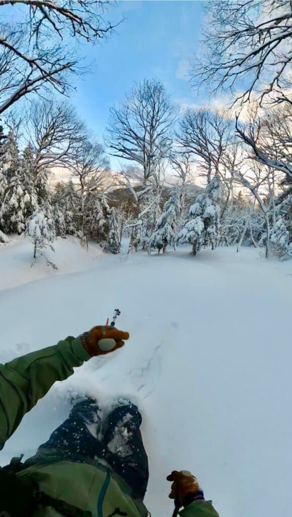 A stunning winter scenery at Bolton Valley in Vermont, USA, showing a ski resort amid snow-covered slopes. There's a skier in action, adding life to the tranquil winter sports scene.