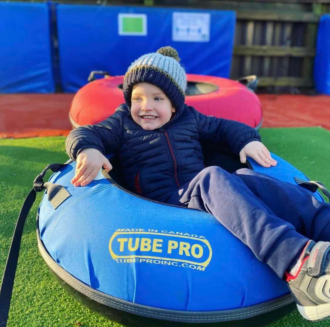 Stoke Ski Centre in United Kingdom - a young boy is sitting on a tube tube.