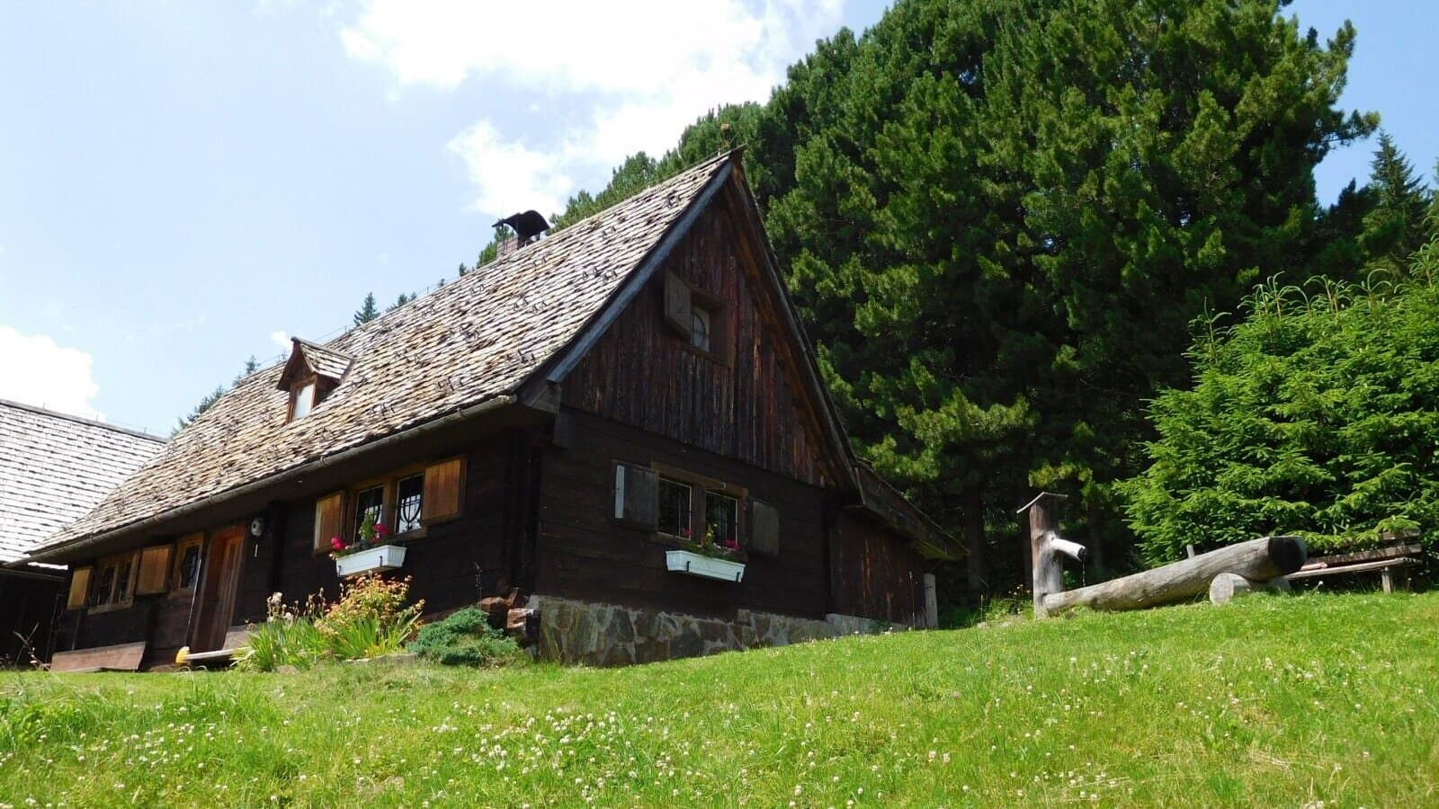 Katschwald in Austria - a wooden house sitting on top of a lush green hillside.
