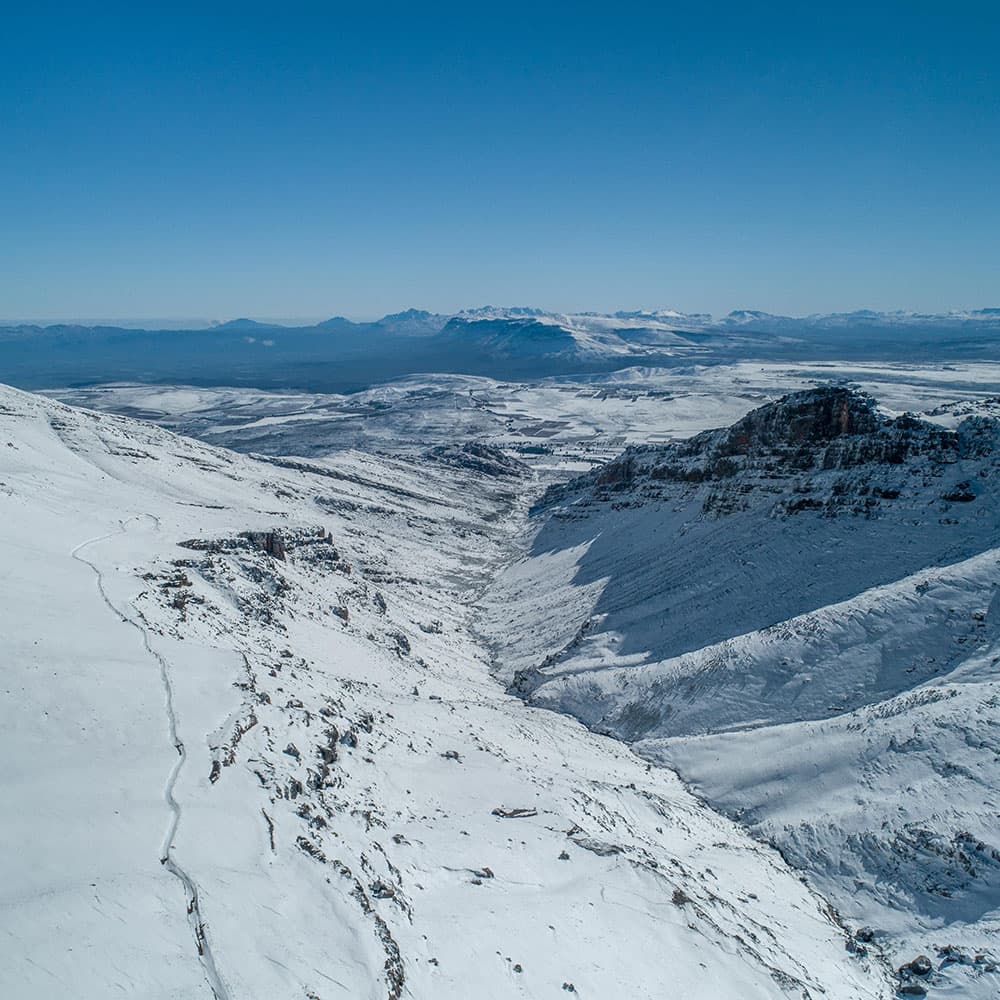 Winter sports scene at Matroosberg, Western Cape, South Africa showcasing a chalet beside the snow-covered slopes of a mountain.