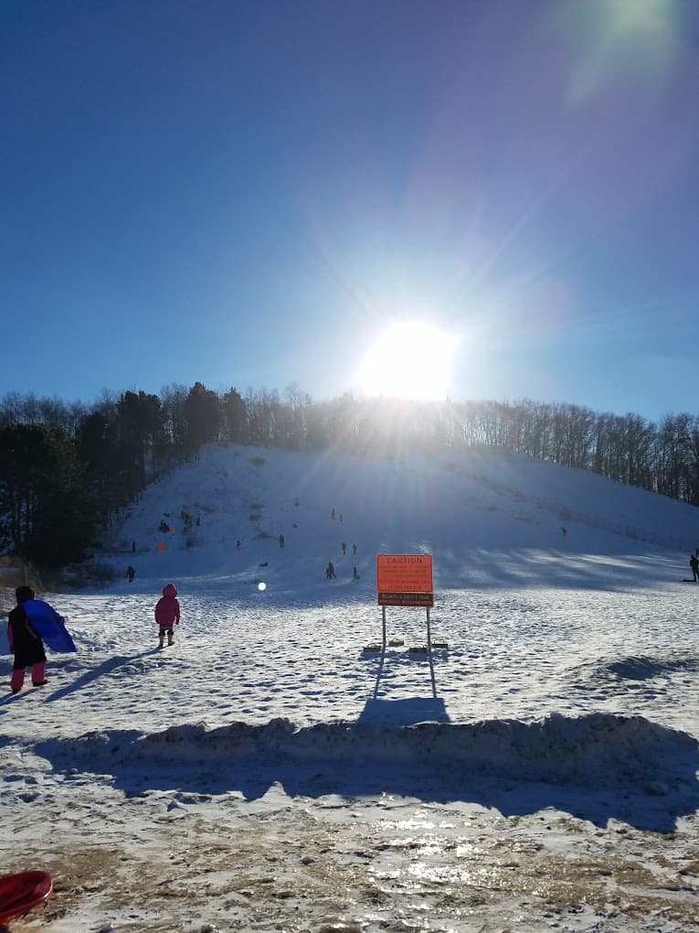Winter sports scene at Pinehurst Park in Eau Claire, Wisconsin, featuring a snow-laden landscape dotted with skiers and snowboarders enjoying the crisp winter day.