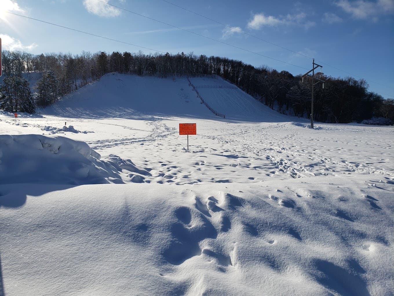 Winter sports activity in full swing at Pinehurst Park, Eau Claire, Wisconsin, with various people engaging in sports, a chalet and a ski resort seen amidst stunning winter scenery.