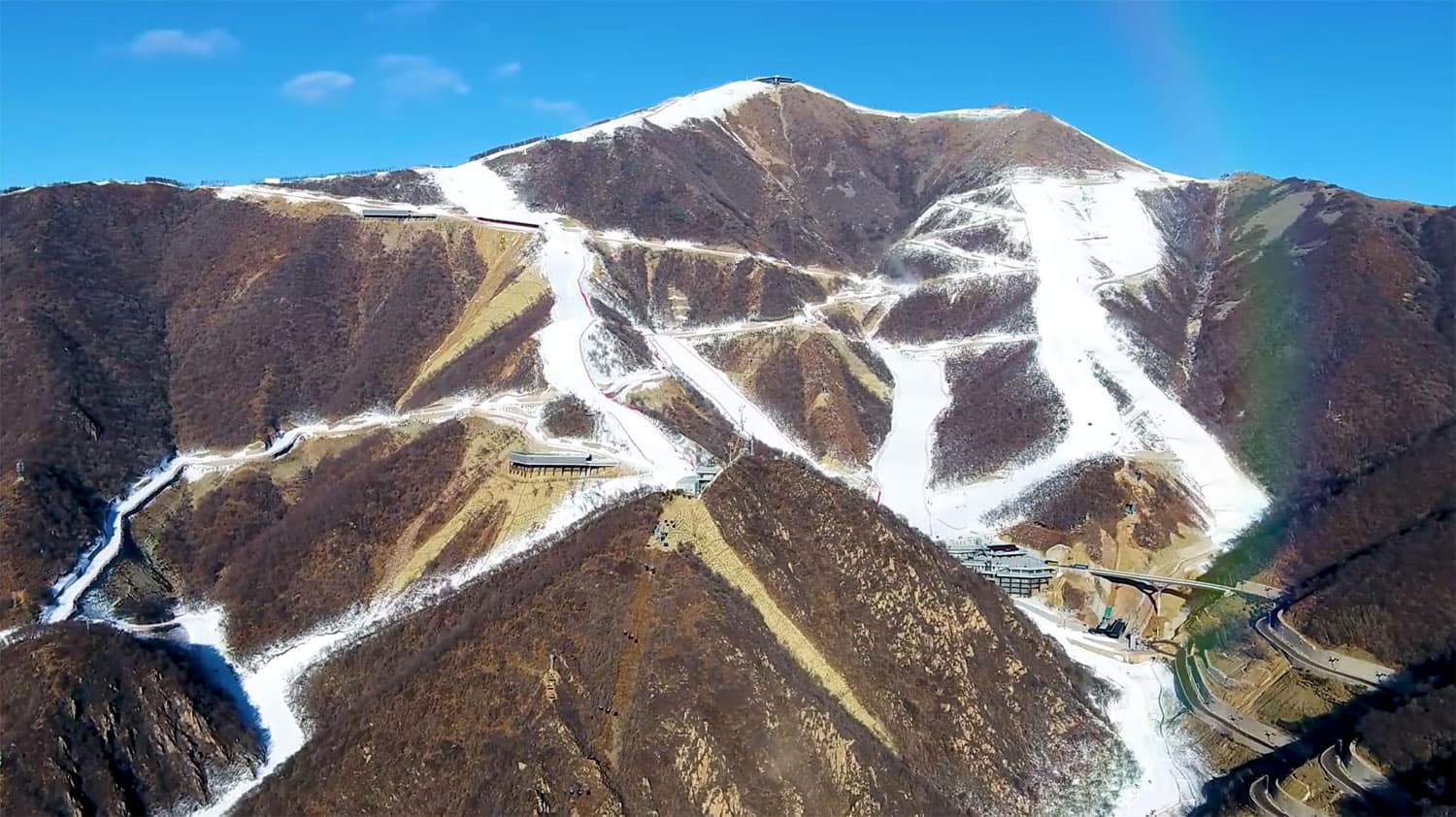 Yanqing National Alpine Ski Centre in China - a rainbow in the sky over a mountain.