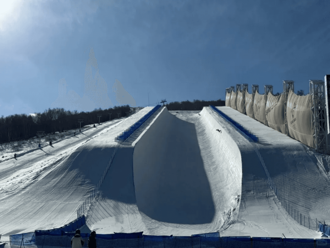 Thaiwoo Ski Resort in China - a snowboarder is going down the side of a hill.