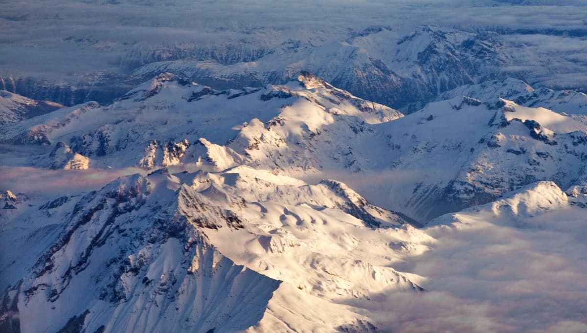 A winter scene at Pantheon in Cariboo Chilcotin Coast British Columbia Canada showcases a majestic mountain with snowy peaks. A chalet sits nestled amidst the snow-covered slopes where winter sports are underway.