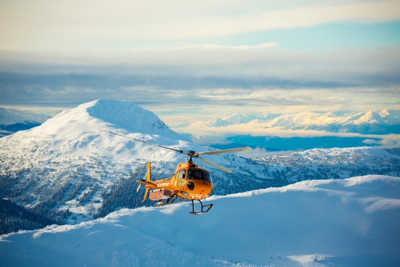 A skier and snowboarder enjoying the snow-covered slopes of Skeena Heliskiing in Northern British Columbia Canada. The ski lift and snowmobile add to the bustling winter sports scene.