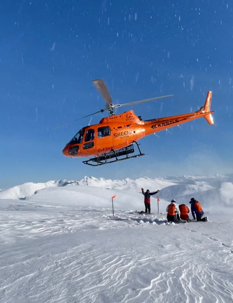 A skier gliding down snow-covered slopes of Skeena Heliskiing resort in northern British Columbia Canada with a ski lift outlined in the background. An image that beautifully captures winter sports at a ski resort.
