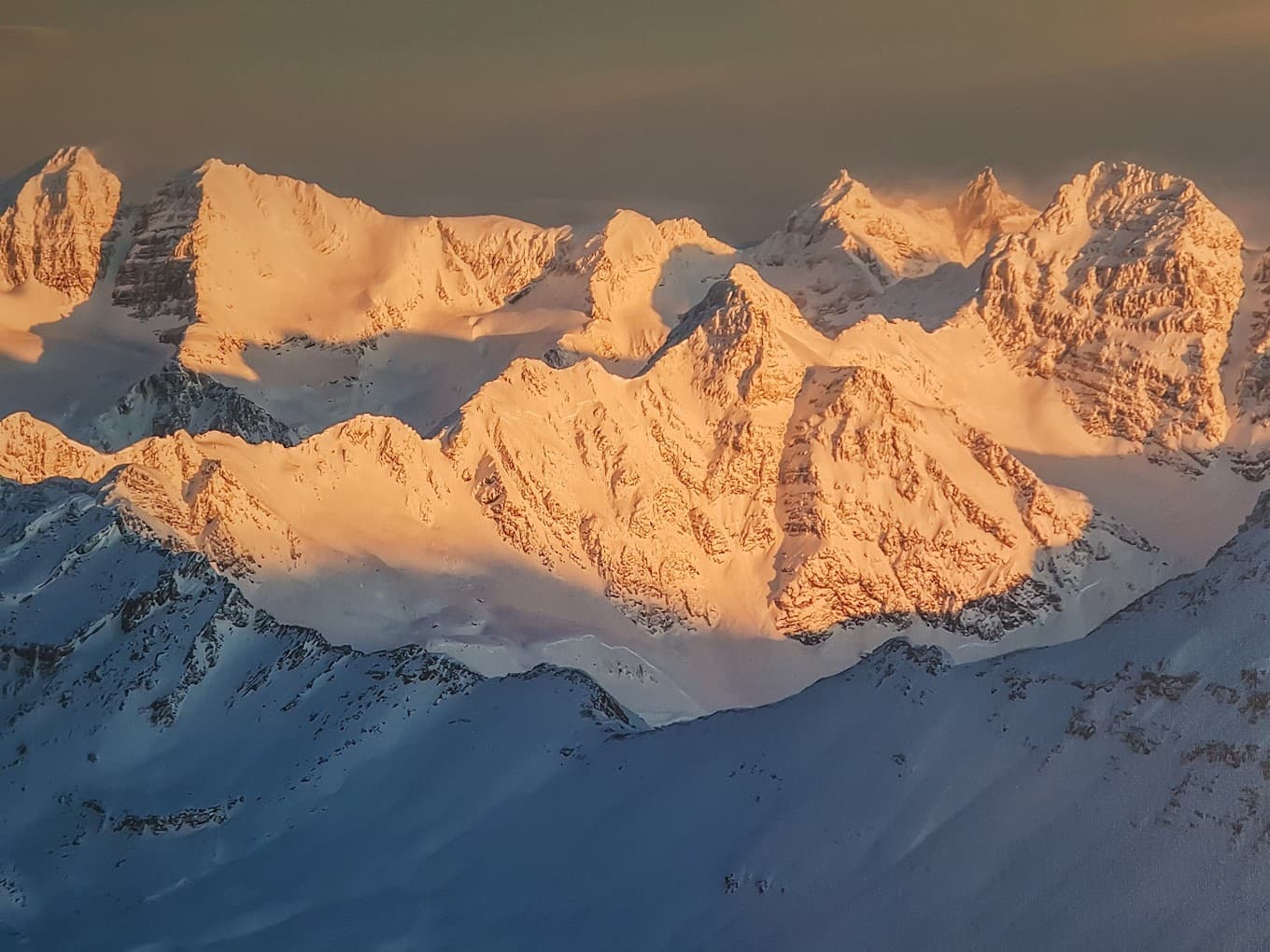 Scenic view of a sunlit snowy mountain in Bobby Burns British Columbia with a chalet nestled by its base suggesting a winter sports location.