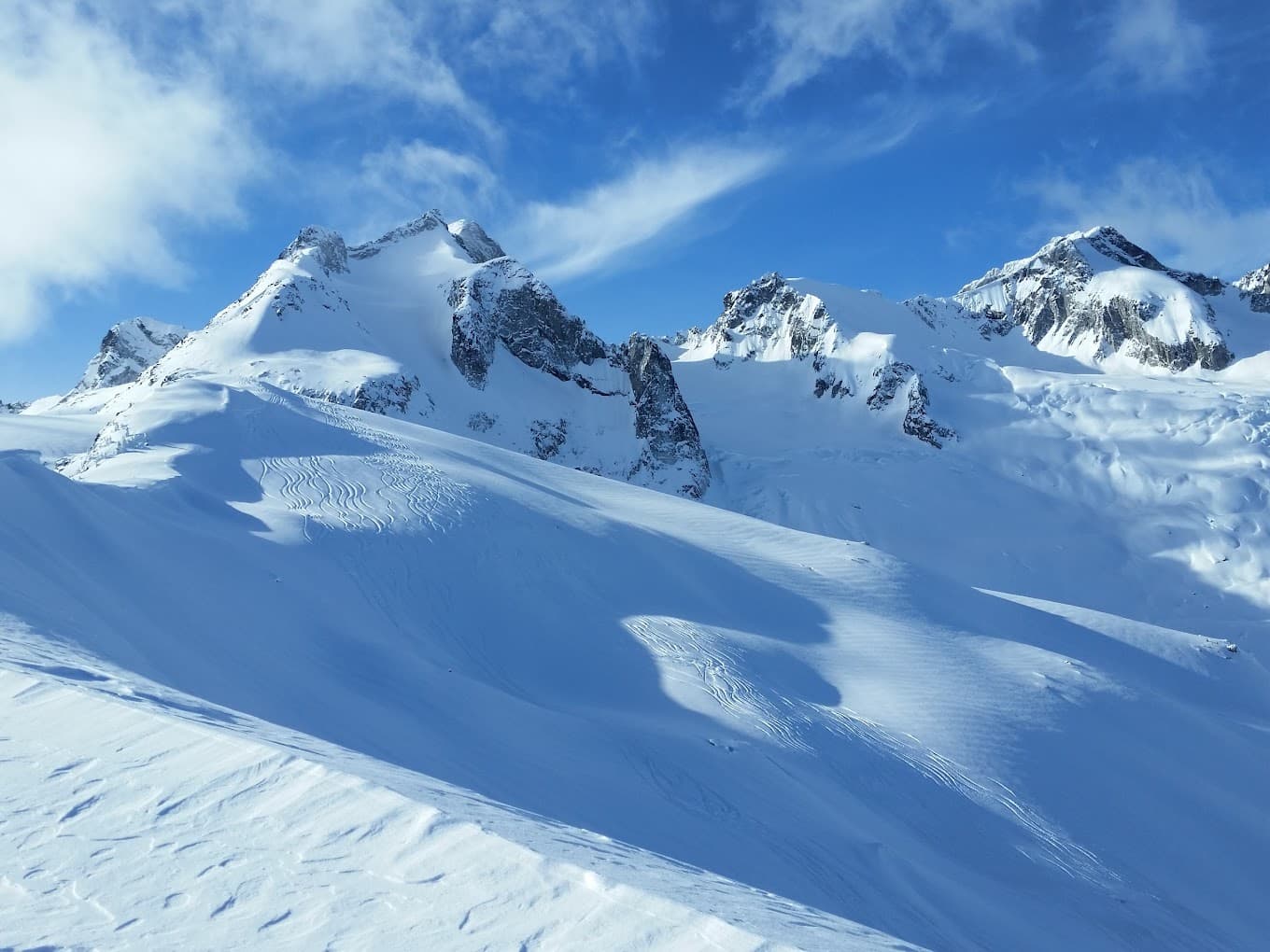 A snowy winter sports scene in Bobby Burns, British Columbia, featuring a charming chalet nestled at the base of a majestic, snow-covered mountain with pristine, glistening slopes ready for action.