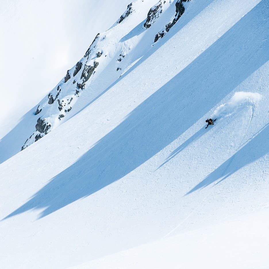 A skier in action at Tyax Heliskiing in British Columbia, Canada, participating in winter sports amidst other skiing enthusiasts at a ski resort.