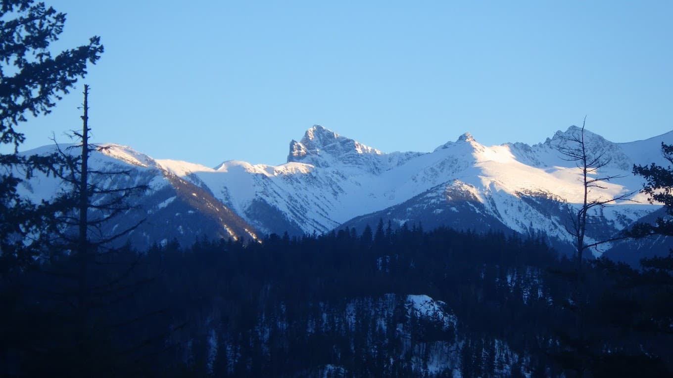 A beautiful scene at Tyax Heliskiing in British Columbia Canada showing a chalet nestled beside a rugged mountain covered in snow creating an idyllic winter sports and scenic setting.