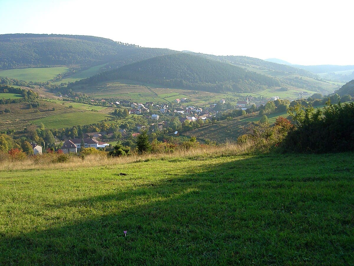 Snow Sun – Horný Vadičov in Slovakia - a green field with a small town in the distance.