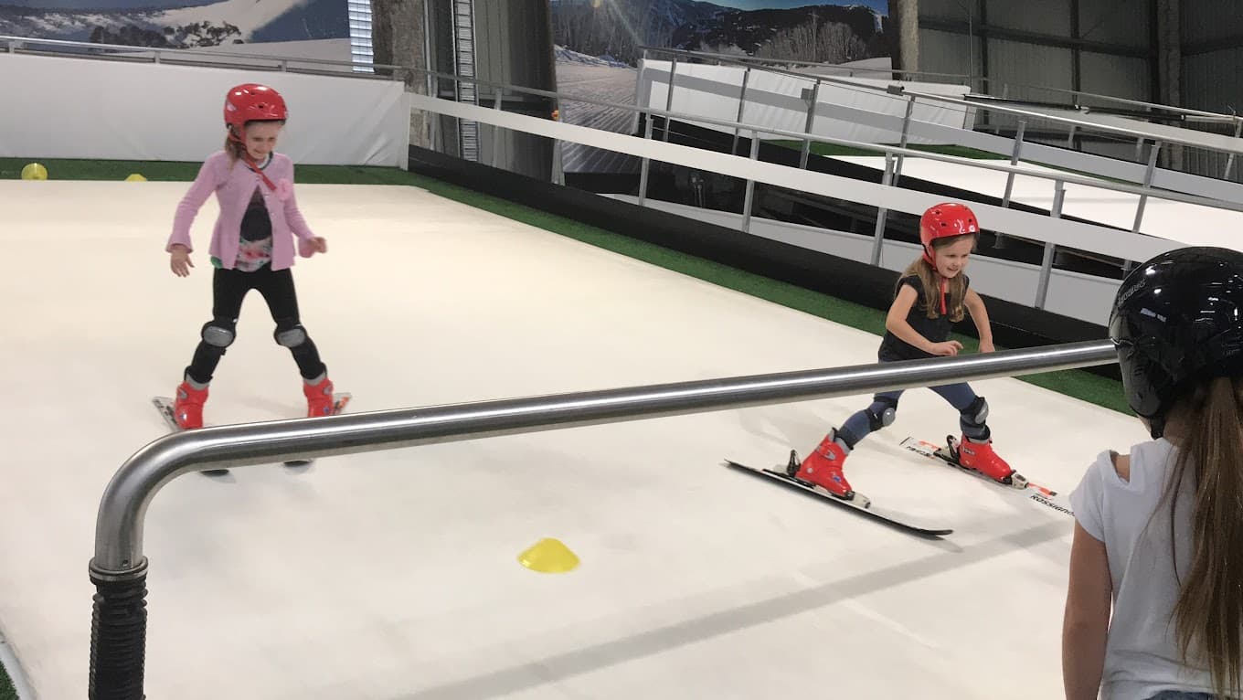 A child learning to ski at the winter sports centre, Urban Xtreme, in Brisbane, Australia with family members also skiing.