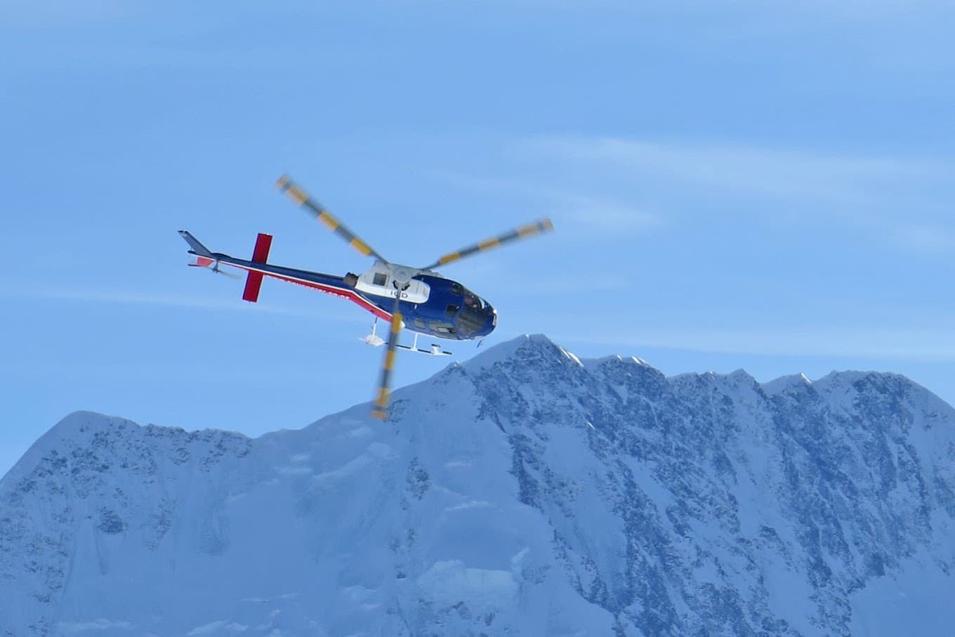 A skier navigating the snowy slopes of Tasman Glacier South Island New Zealand. Surrounding scenery includes a distant chalet amidst the winter sports scene.