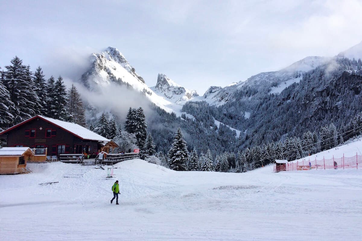 Thollon les Mémises in France - a person standing in the snow near a cabin.