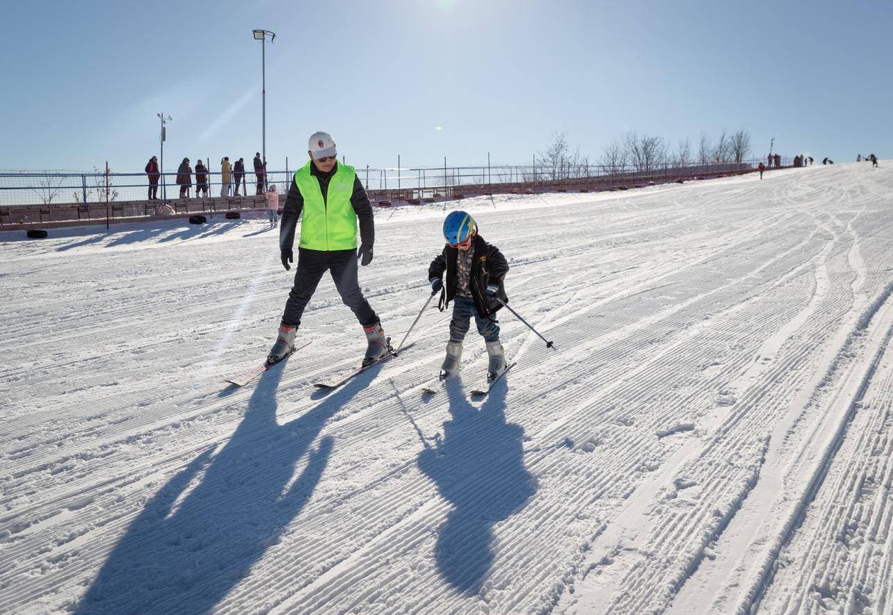 Lvxinchun in China - two people cross country skiing in the snow.