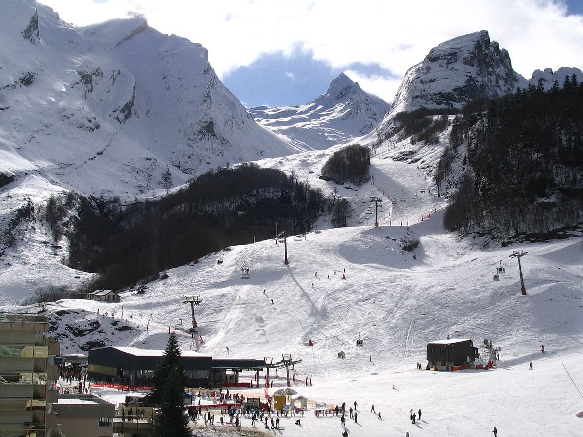 Station Gourette in France - a group of people skiing down a snow covered mountain.