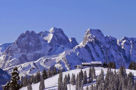 A scenic view of the popular ski resort in Innerkrems, Carinthia, Austria in winter. Vibrant snow-covered mountain peaks and busy winter sports enthusiasts create a captivating scene.