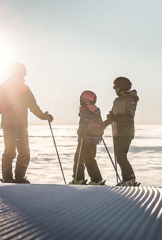 A family enjoying a day of skiing at Hochficht in Mühlviertel Upper Austria. The winter sports scene includes adults and a child showcasing a joyful active day in the snow.