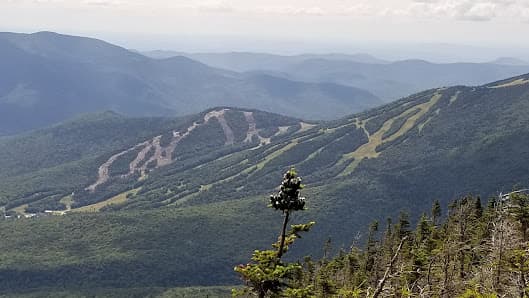 A picturesque view of Waterville Valley Resort in New Hampshire USA showcasing a vast mountain landscape perhaps with faint glimpses of a ski resort and chalet.