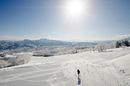 Winter sports enthusiasts engage in activities at the Myoko Akakura Kanko ski resort in Myoko, Honshu, Japan. The scene is set against a backdrop of stunning winter scenery.