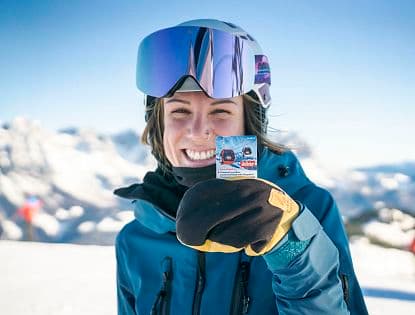 A skier and a snowboarder enjoying a winter sports scene at SkiWelt Brixental resort in Tyrol, Austria with a charming challet in the background.