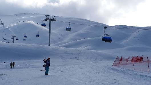 Ski lift at a resort in Nikfer, Tavas/Denizli, Turkey, with a chalet in the background. Skiers are enjoying winter sports in the snowy scene.