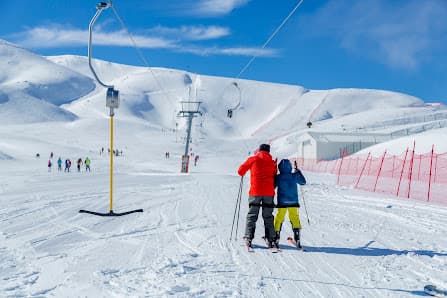 Winter scene at a ski resort in Denizli, Nikfer, Turkey. Skiers navigate snowy slopes near a quaint chalet. The winter sports centre offers an exciting winter escape in the Aegean Region.