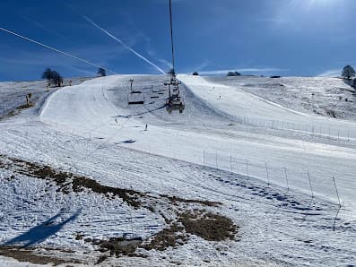 Winter scene at Forni di Sopra ski resort in Italy, featuring a chalet and a ski lift amidst the snow-covered slopes for winter sports activities.