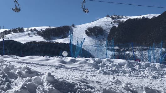 A skier enjoys a day at the Altopiano di Brentonico ski resort in Trentino Italy. On the slopes under a ski lift the lively winter sports scene is complemented by a cozy chalet nearby.