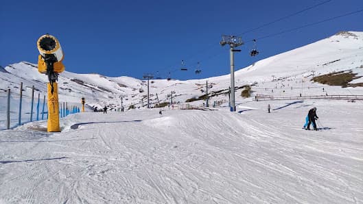 A picturesque view of Alto Campoo ski resort in Cantabria Spain featuring a charming chalet a bustling winter sports scene anchored by a ski lift all surrounded by a crisp winter landscape.