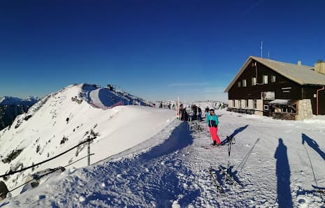 Winter sports enthusiasts enjoying a day at the Hochkar Bergbahnen ski resort in Lower Austria, featuring a ski lift, chalet, and bustling winter sports centre.