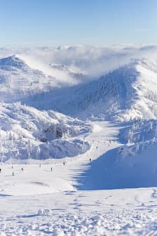 Winter sports enthusiasts enjoying a beautiful day on the snow-covered slopes of Hochkar Bergbahnen ski resort in Lower Austria, showcasing winter scenery at its best.