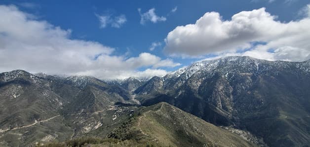 Stunning view of Mt Baldy in California, with a challet nestled at the foothills. The mountain ranges are distant yet prominent under a bright, sunny day.