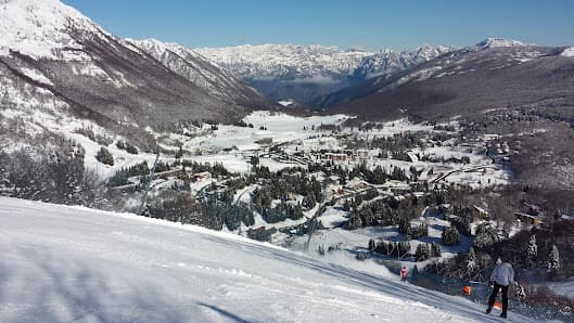A picture of a chalet at Piancavallo ski resort in Italy featuring snow-covered slopes being enjoyed by winter sports enthusiasts.