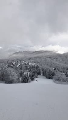 A chilling scenic view of Piancavallo in Italy featuring a charming chalet amidst a bustling ski resort surrounded by remarkable winter scenery and majestic mountains.